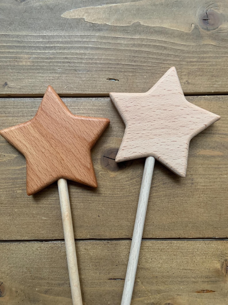 Puede incluir: Dos varitas con forma de estrella hechas de madera. Una estrella est&aacute; elaborada con madera de color marr&oacute;n rojizo oscuro, mientras que la otra es de madera de color beige claro. Cada estrella est&aacute; unida a un mango cil&iacute;ndrico de madera.