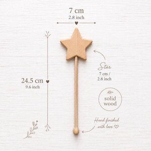 Puede incluir: Una varita de estrella de madera de color marr&oacute;n claro que mide 24,5 cm de longitud total con una parte superior de 7 cm. El texto en la imagen indica que es de madera maciza y est&aacute; acabada a mano. El ancho de la estrella es de 7 cm y la altura es de 24,5 cm.