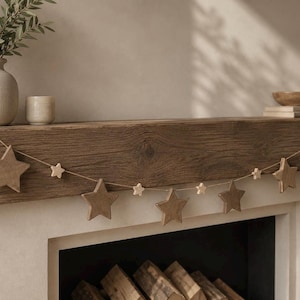 Può includere: Una ghirlanda decorativa composta da stelle in legno di dimensioni alternate, grandi e piccole, infilate su un sottile spago. Le stelle presentano una finitura in legno marrone naturale e sono distanziate uniformemente lungo la corda.