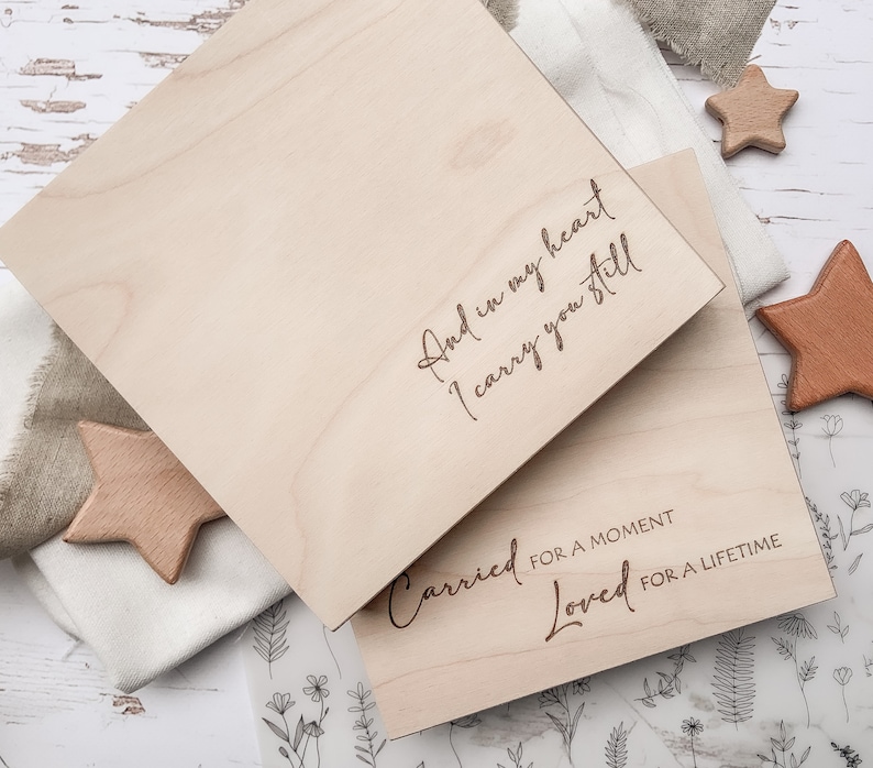 May include: Two wooden boxes with engraved text. The top box reads "And in my heart I carry you still". The bottom box reads "Carried for a moment Loved for a lifetime".