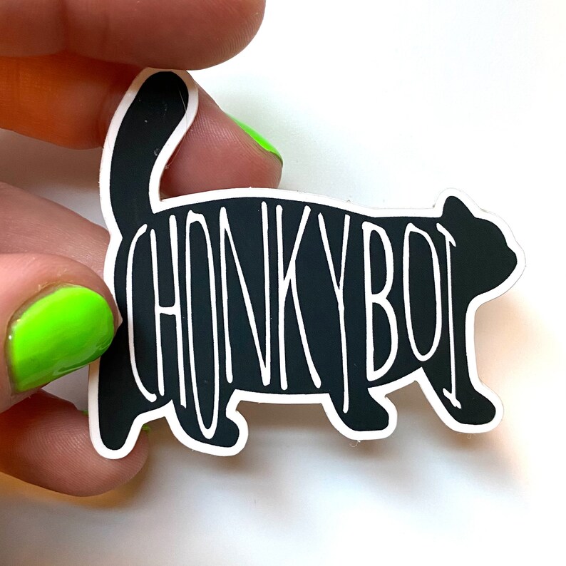 Op de afbeelding: Zwart-witte sticker van een cartoonkat met de tekst "CHONKY BOI" erop.