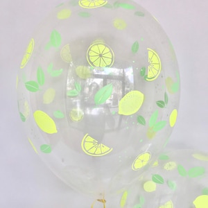K&ouml;nnte beinhalten: Transparentem Plastikballon mit einem Zitronen- und Blattdesign. Der Ballon ist aufgeblasen und mit einem goldenen Band gebunden.