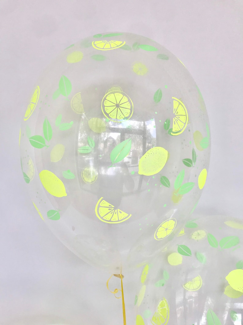 K&ouml;nnte beinhalten: Transparentem Plastikballon mit einem Zitronen- und Blattdesign. Der Ballon ist aufgeblasen und mit einem goldenen Band gebunden.