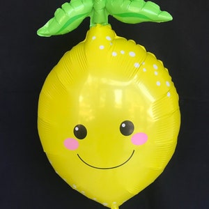 Puede incluir: Un globo amarillo con forma de lim&oacute;n con una hoja verde en la parte superior. El globo tiene un patr&oacute;n de lunares blancos y una cara sonriente con mejillas rosadas.