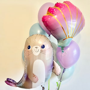 May include: A set of five balloons featuring a seal, a seashell, and three solid color balloons in shades of purple, blue, and pink.