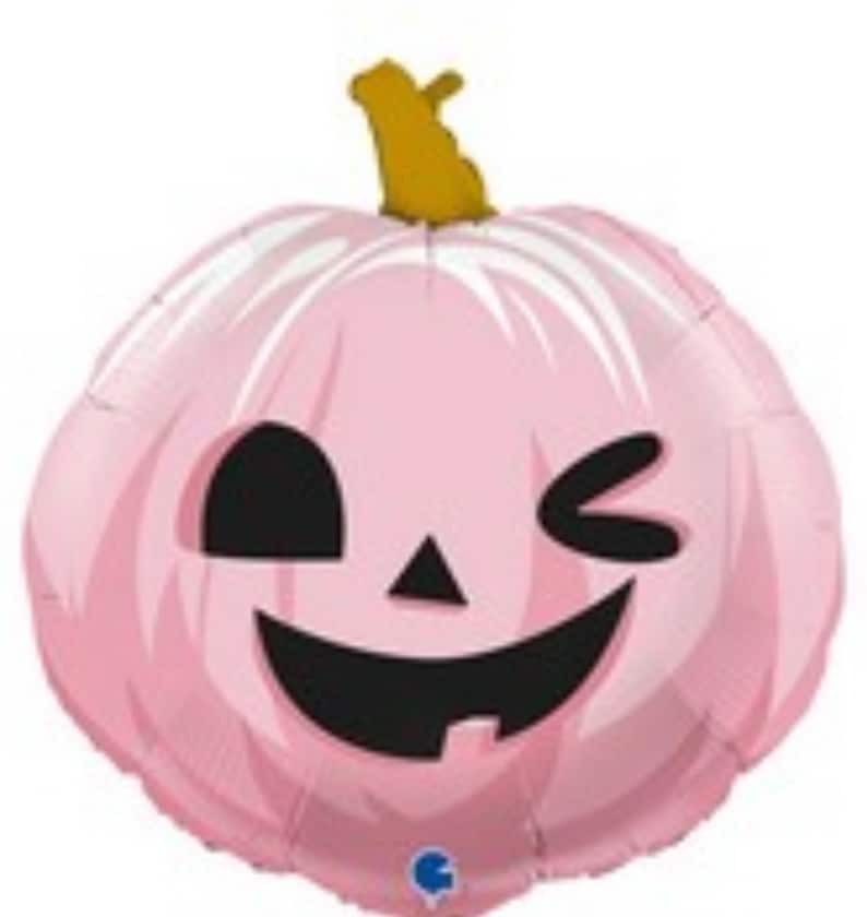 Op de afbeelding: Een roze pompoenballon met een knipperend gezicht en een zwarte glimlach. De ballon is versierd met witte lijnen.