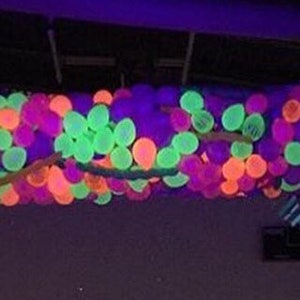 May include: A ceiling decorated with a large cluster of neon green, pink, and purple balloons.