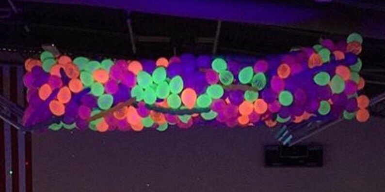 May include: A ceiling decorated with a large cluster of neon green, pink, and purple balloons.
