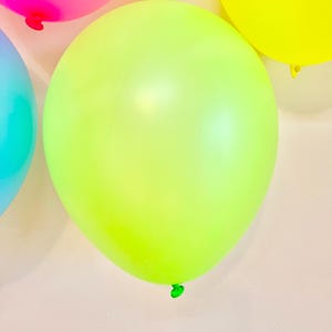 May include: A group of colourful balloons, including pink, yellow, and light green, against a white background.