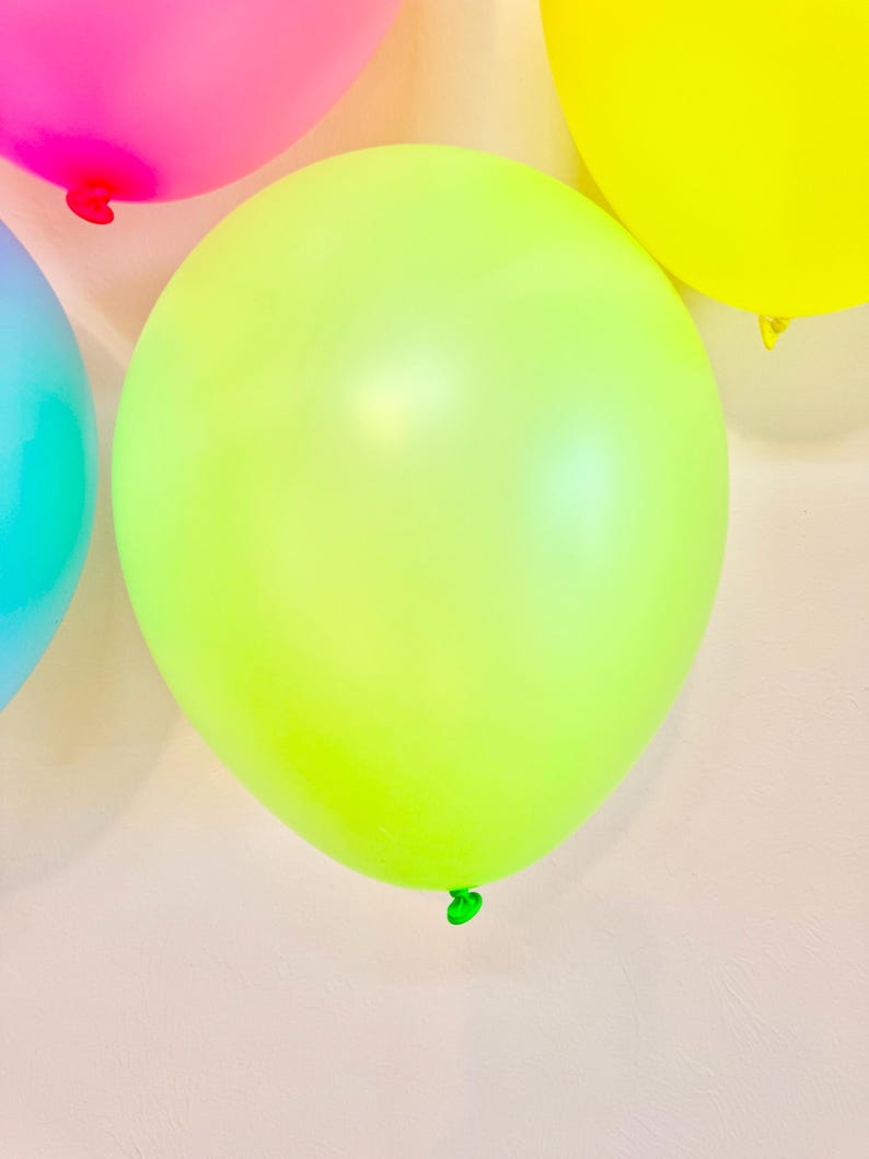 May include: A group of colourful balloons, including pink, yellow, and light green, against a white background.