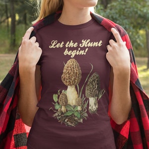 May include: A maroon t-shirt with a graphic of morel mushrooms and the text "Let the Hunt begin!"