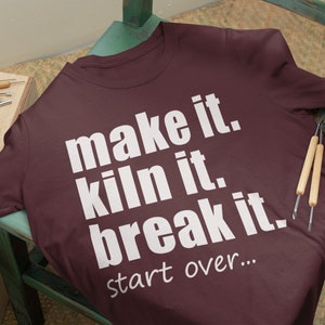 May include: A maroon t-shirt with white text that reads "make it. kiln it. break it. start over..."