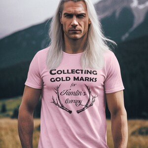 May include: A pink t-shirt with the text "COLLECTING GOLD MARKS for Tamlin's therapy" and a graphic of antlers.