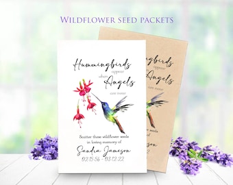 May include: White wildflower seed packet with a watercolor hummingbird illustration and the text "Hummingbirds appear when Angels are near." The packet includes the name Sandra Jameson and dates 02.15.56 - 03.12.22. A second packet is visible, along with lavender.