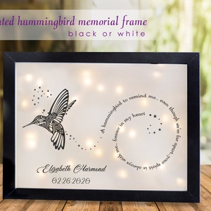 May include: A black framed lighted memorial with a hummingbird silhouette and the text "A hummingbird to remind me... even though we're far apart... you're always in my heart."  The name "Elizabeth Hammond" and the date "02-26-2026" are also included.