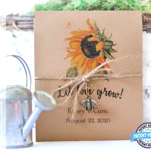 May include: A kraft paper seed packet featuring a watercolor sunflower illustration. The packet is tied with twine and adorned with a bee charm. Text includes "Let love grow!" and a date. A watering can is in the background.