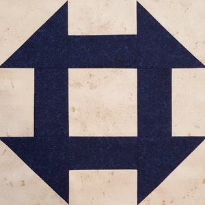 May include: A quilt block with a white background and navy blue squares and triangles. The design is a simple geometric pattern.