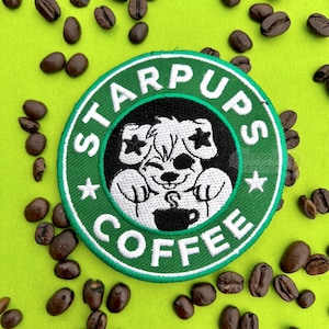 May include: Embroidered patch with the text "STARPUPS COFFEE" in a green and white circular design. The patch features a cartoon dog holding a coffee cup. Coffee beans are scattered around the patch on a green background.