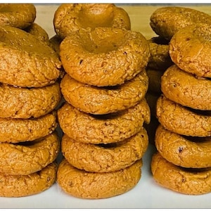 May include: A stack of golden brown, round, sweet treats, possibly cookies or pastries, arranged in a pyramid shape.