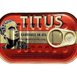 May include: A red and gold Titus sardine can. The can features a black and white illustration of a man's face. The text "Sardines in Oil" and "Net Weight 4 3/8 oz (125g)" are also visible.