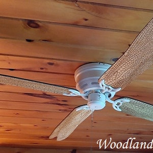 May include: White ceiling fan with four blades. The blades are painted with a wood grain pattern and have a light brown color. The fan is mounted on a wooden ceiling.