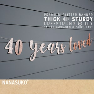 May include: Rose gold glitter banner with the text "40 years loved". The banner is pre-strung and comes with a thick, sturdy construction.