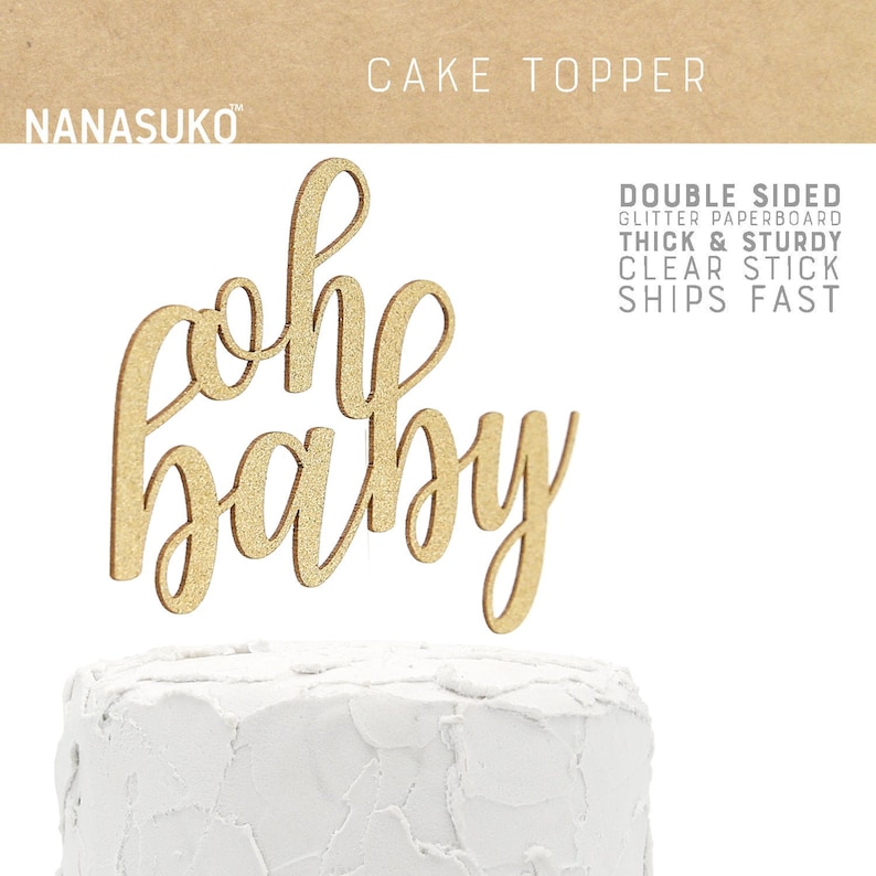 Puede incluir: Topper para pastel de cart&oacute;n con purpurina dorada con las palabras "oh baby" en letra cursiva. El topper est&aacute; encima de un pastel blanco glaseado.