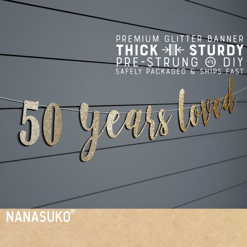 May include: Gold glitter banner with the text "50 years loved" on a gray wood background. The banner is pre-strung and comes with instructions for DIY assembly.  The banner is thick and sturdy, and is safely packaged and ships fast.