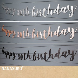 May include: Three happy 30th birthday banners in silver, rose gold, and black glitter. The banners are strung on white string and are hanging against a gray background. The text "NANASUKO&reg;" is printed in the bottom right corner.