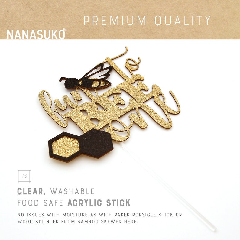 May include: Gold glitter cake topper with the text "Let's bee one" and a black and yellow bee. The topper is attached to a clear acrylic stick.