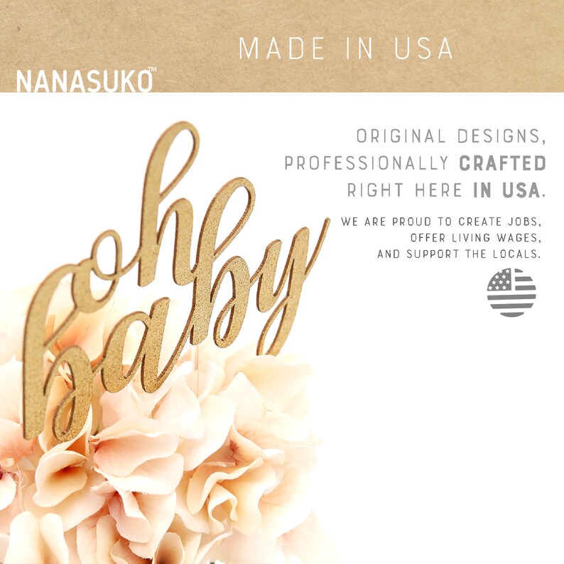 Puede incluir: Topper de pastel de madera dorada con las palabras "oh baby" en una fuente cursiva. El topper est&aacute; sentado encima de un ramo de flores de color rosa p&aacute;lido. El fondo es una superficie blanca con el texto "MADE IN USA" y un mensaje sobre el apoyo a las empresas locales.