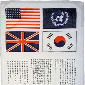 May include: A white fabric towel with four flags printed on it. The flags are the American flag, the United Nations flag, the British flag, and the South Korean flag. The text below the flags reads "I am an American UNITED NATIONS.  ...  Help us and we will help you."