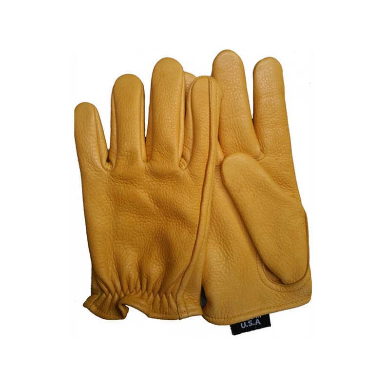 May include: A pair of work gloves made of tan leather. The gloves have a textured surface and a reinforced palm. The gloves are labeled "U.S.A." on a small black tag. The gloves are designed for protection and grip.