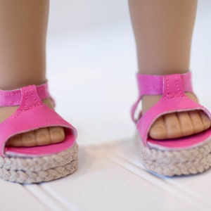 May include: Pink platform sandals with a woven sole and adjustable ankle straps.