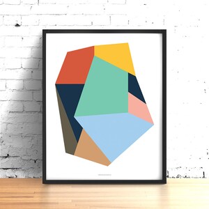 May include: Abstract geometric art print featuring a multi-colored, irregular shape with shades of blue, green, yellow, orange, brown, and pink. The print is framed in black.