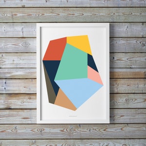 May include: Abstract geometric art print featuring a multi-colored shape with shades of blue, green, yellow, red, pink, brown, and black. The print is framed in a white frame.