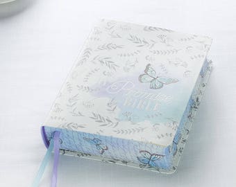 Könnte beinhalten: Eine weiße und blaue Bibel mit einem Schmetterlingsdesign und dem Text "My Promise Bible". Der Einband zeigt einen aquarellartigen Hintergrund mit zarten Blumenmustern.