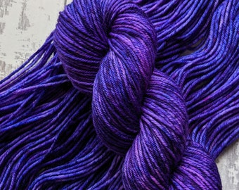 May include: A skein of deep purple yarn with a variegated color pattern. The yarn is soft and has a subtle sheen.