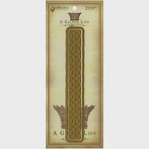 May include: A die set package featuring a long, ornate, gold-colored die with a detailed pattern. The package has the text "A Gilded Life" and "Spellbinders" branding. The die set is designed for crafting and paper projects.