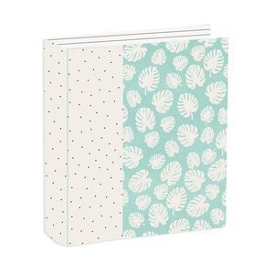 Puede incluir: Un álbum de fotos blanco con una cubierta de patrón azul verdoso y blanco. Un lado de la cubierta presenta un patrón de lunares blancos sobre un fondo crema. El otro lado presenta un fondo azul verdoso con siluetas de hojas tropicales blancas.
