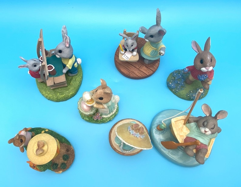 Puede incluir: Un conjunto de 8 figuritas de conejo de cer&aacute;mica pintadas a mano. Cada conejo est&aacute; vestido con ropa diferente y tiene una personalidad &uacute;nica. Los conejos est&aacute;n sentados en varias bases, incluyendo una escuela, un barco y una maceta.