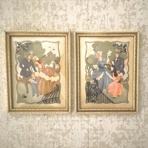 May include: Two framed vintage prints with gold-colored ornate frames. Each print depicts a family scene in a garden setting, with figures in period clothing. The artwork features soft colors and a romantic theme.