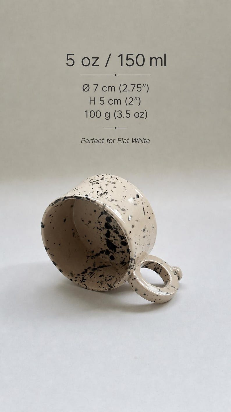 May include: A beige ceramic mug with black splatter details. The mug has a rounded handle and is 2 inches high, 2.75 inches in diameter, and weighs 3.5 oz. The text on the image reads "5 oz / 150 ml" and "Perfect for Flat White."