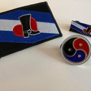 Könnte beinhalten: Drei gestickte Patches mit verschiedenen Symbolen. Der erste Patch ist blau, weiß und schwarz mit einem roten Herzen und einem schwarzen Stiefel. Der zweite Patch ist blau, weiß und schwarz mit einem roten Herzen und einem schwarzen Stiefel. Der dritte Patch ist ein schwarzes, rotes und blaues Yin-Yang-Symbol.