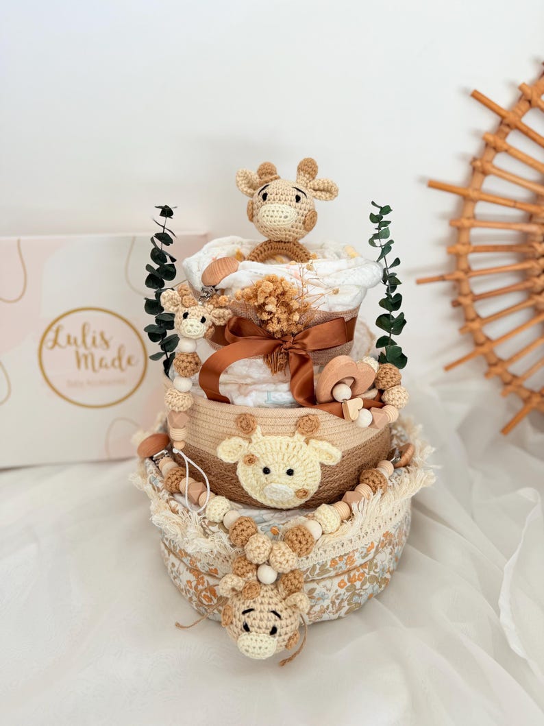 Windeltorte mit gehäkelter Giraffe in beigen Erdtönen, dekoriert mit Holzperlen und Schleife, Geschenkidee für Babyshower oder Taufe.