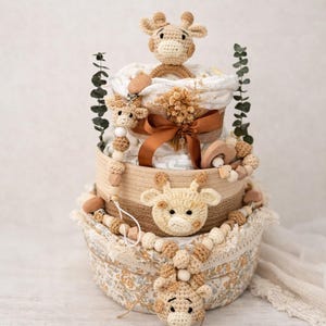 K&ouml;nnte beinhalten: Ein mehrst&ouml;ckiger Babygeschenkkorb mit Giraffen-Motiv. Der Korb enth&auml;lt geh&auml;kelte Giraffen, Holzperlen und ein braunes Band. Er ist mit Windeln und anderen Babyartikeln gef&uuml;llt. Das Farbschema ist neutral mit Beige- und Braunt&ouml;nen.