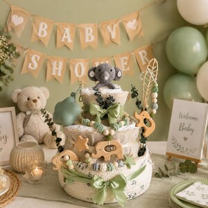 May include: A baby shower display featuring a diaper cake decorated with green bows, wooden animal cutouts, and a gray crocheted elephant. The scene includes balloons, a banner that says "Baby Shower", and a sign that says "Welcome Baby".