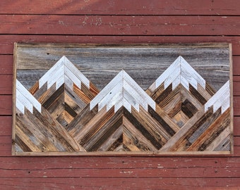 May include: A wooden wall art piece depicting three mountains with white peaks. The mountains are made of reclaimed wood and have a rustic, natural look.
