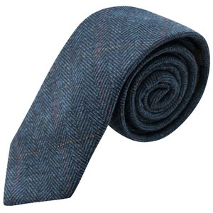 Può includere: Una cravatta blu a spina di pesce arrotolata con accenti rossi e gialli. La cravatta è realizzata in tessuto strutturato e presenta un design classico e formale, ideale per affari o occasioni speciali.