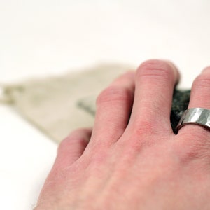 Silver pewter ring 8mm wide with hammered texture and battle damage on mans hand